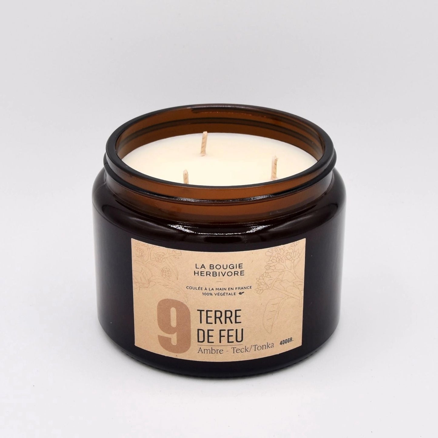 Bougie parfumée ambre teck dans un pot en verre marron avec trois mèches et étiquette élégante