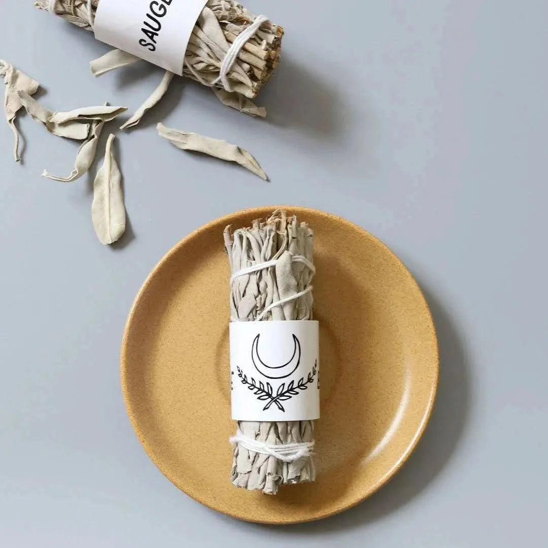 Sauge blanche écologique de La Bougie Herbivore présentée sur une assiette avec des feuilles éparpillées