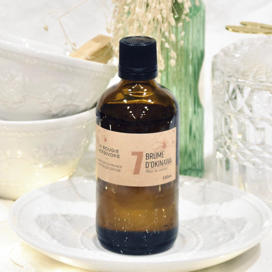 Diffuseur parfum fleur de cerisier de La Bougie Herbivore en bouteille marron sur une belle table décorée