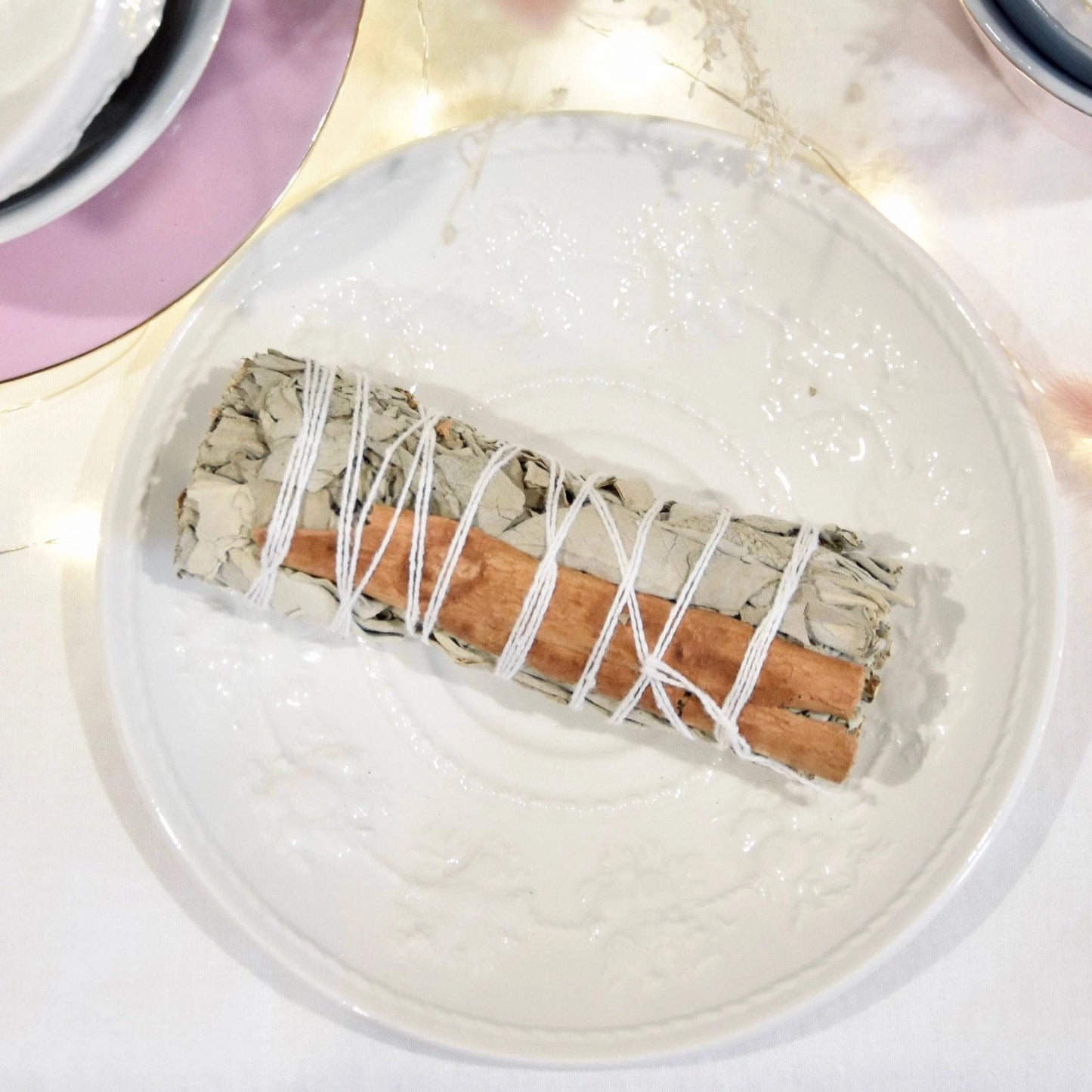 Fagot sauge blanche cannelle de La Bougie Herbivore sur une assiette blanche décorative
