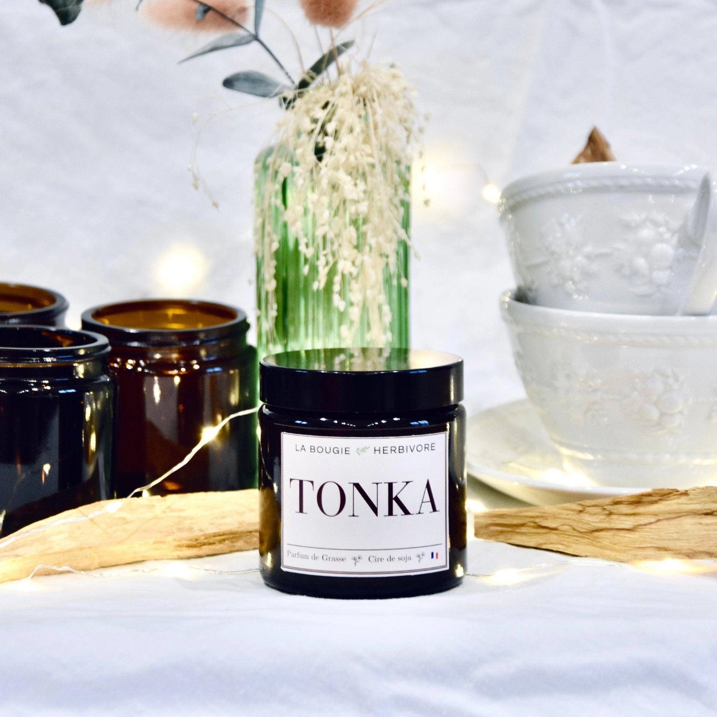 Bougie parfumée Tonka de La Bougie Herbivore avec un élégant pot noir sur une table décorée