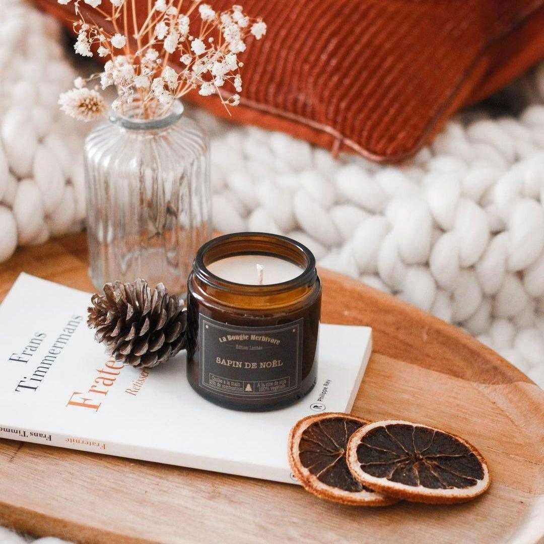Bougie artisanale de Noël dans un pot en verre avec des tranches d'orange séchées et une déco chaleureuse