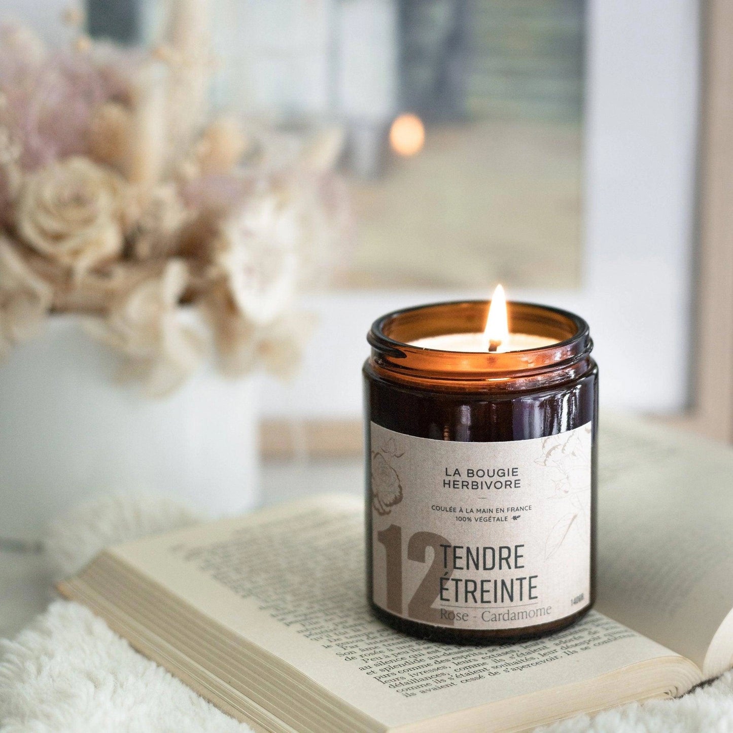 Bougie rose cardamome de La Bougie Herbivore dans un pot en verre avec une flamme allumée