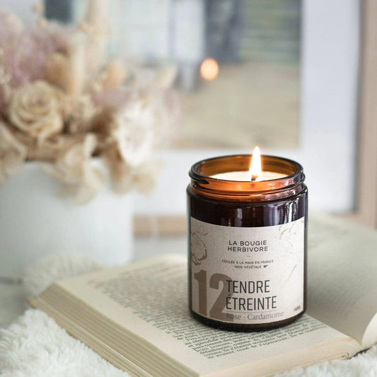 Bougie rose cardamome de La Bougie Herbivore dans un pot en verre avec une flamme allumée