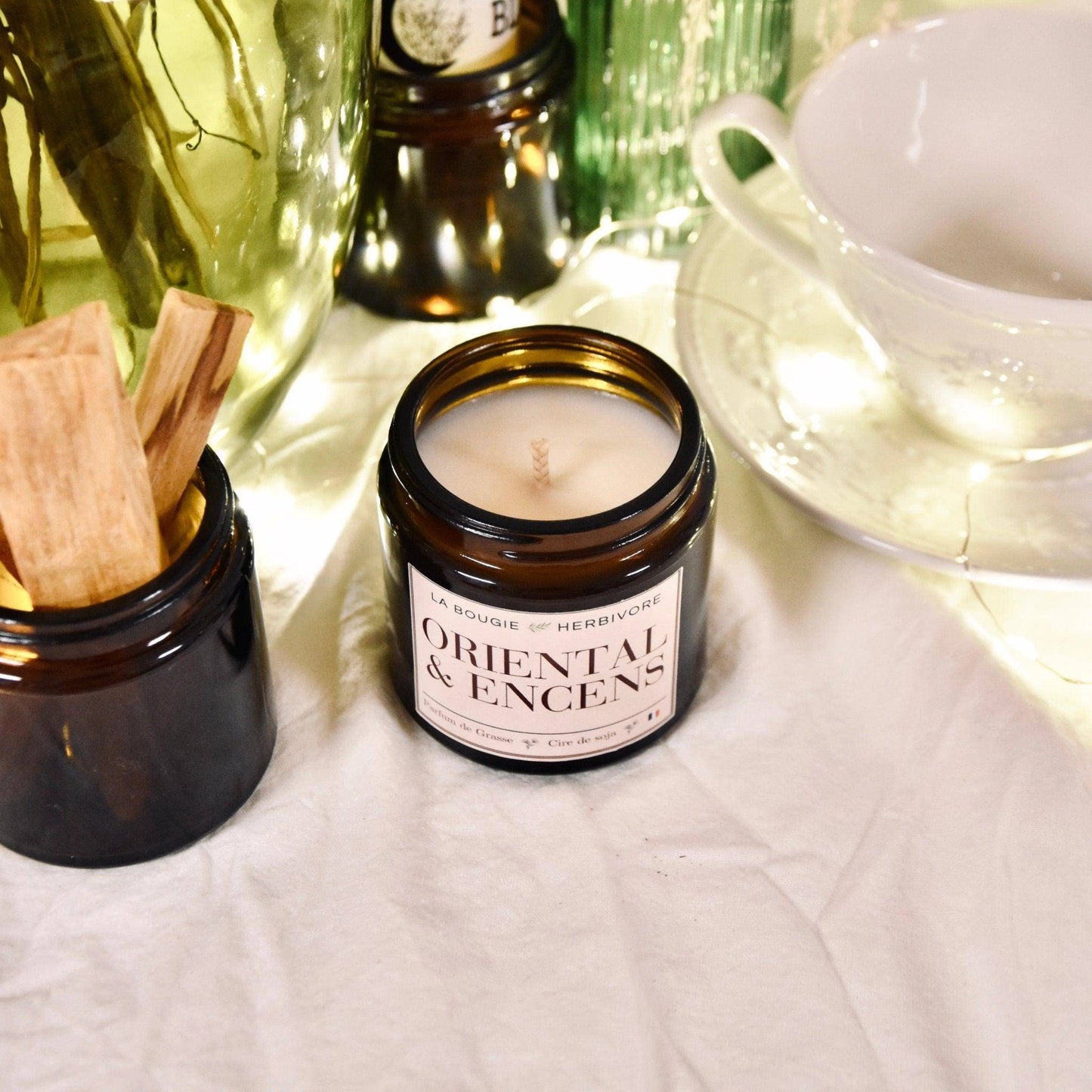 Bougie parfumée orientale dans un pot en verre, décorée avec des bâtons d'encens et un environnement chaleureux