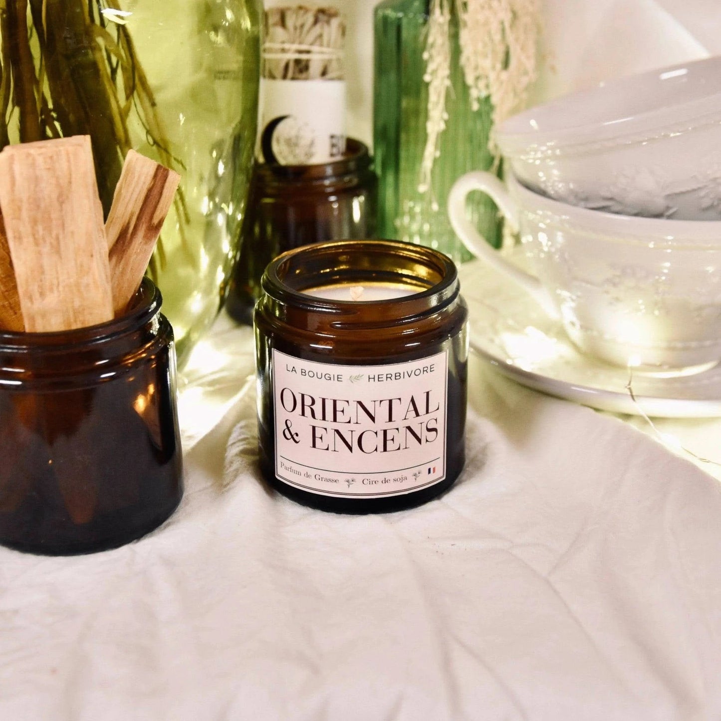 Bougie parfumée orientale La Bougie Herbivore dans un pot en verre brun avec des bâtons de bois
