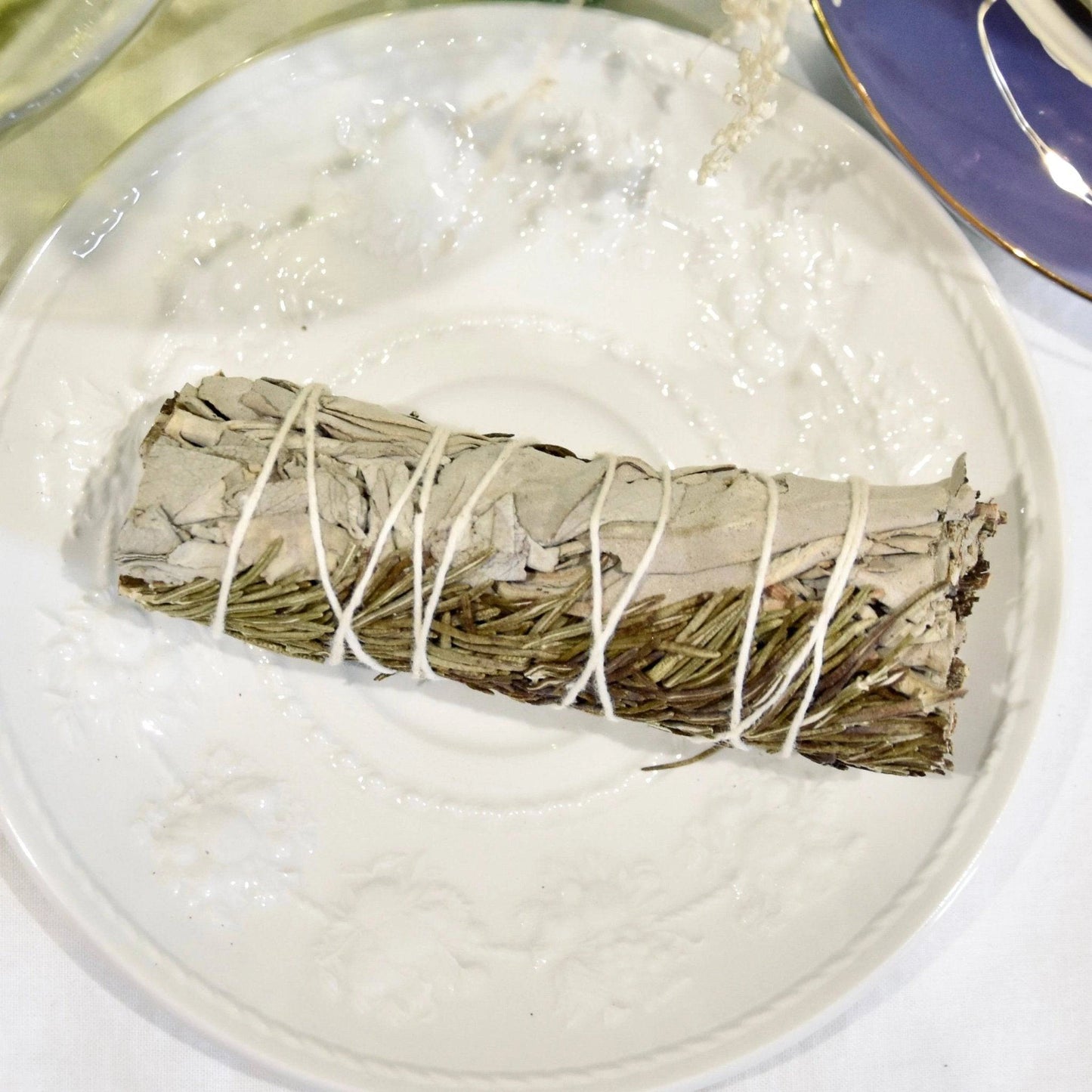 Bâton de sauge et romarin bienfaits de La Bougie Herbivore sur un plat décoratif