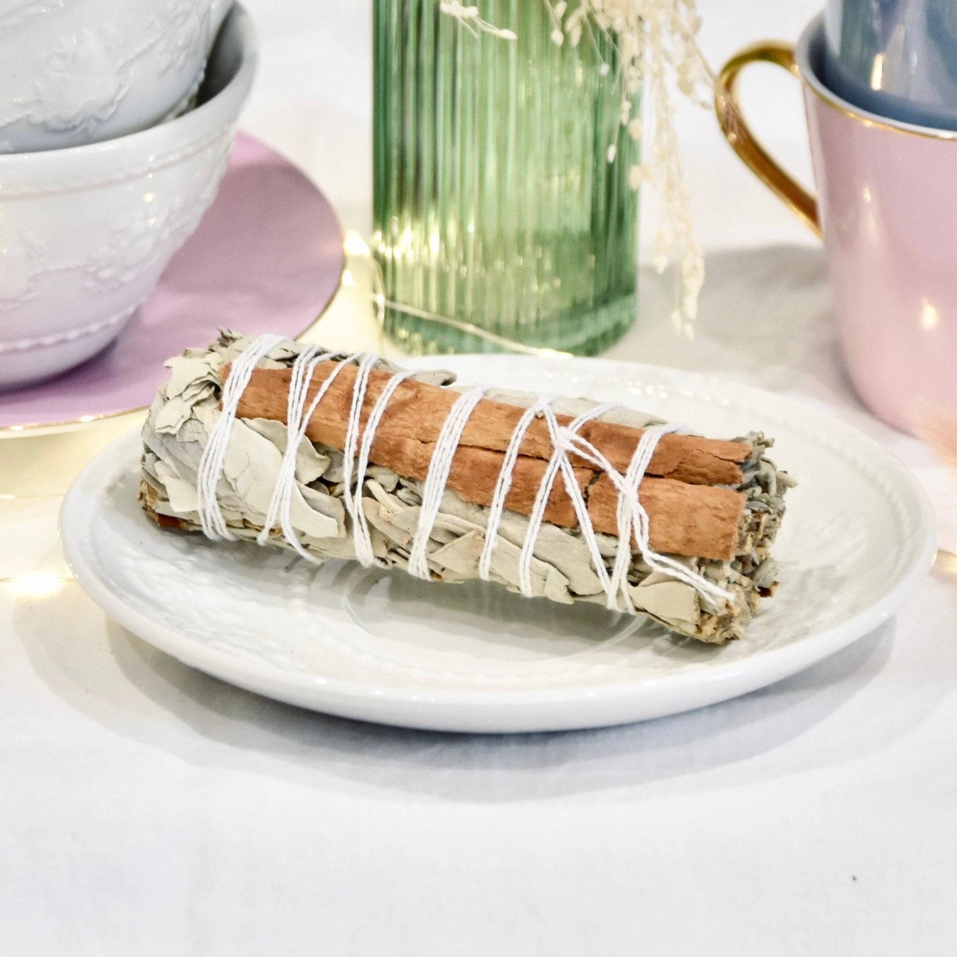 Fagot sauge blanche cannelle sur une assiette blanche au décor élégant pour purification d'espace